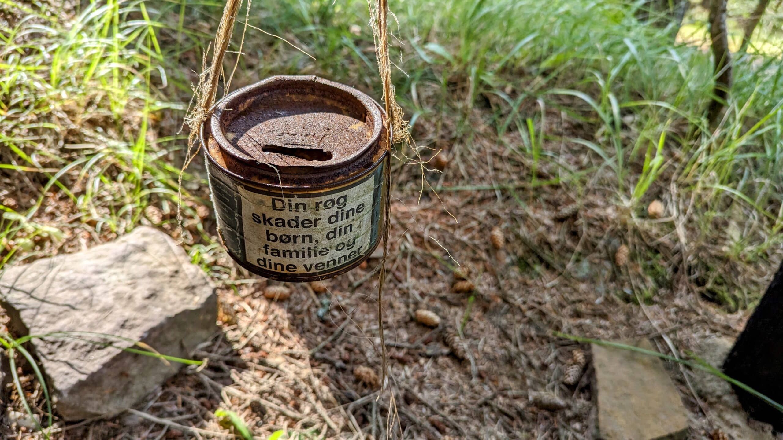 Ein altes Glas, das an einem Seil im Wald hängt.