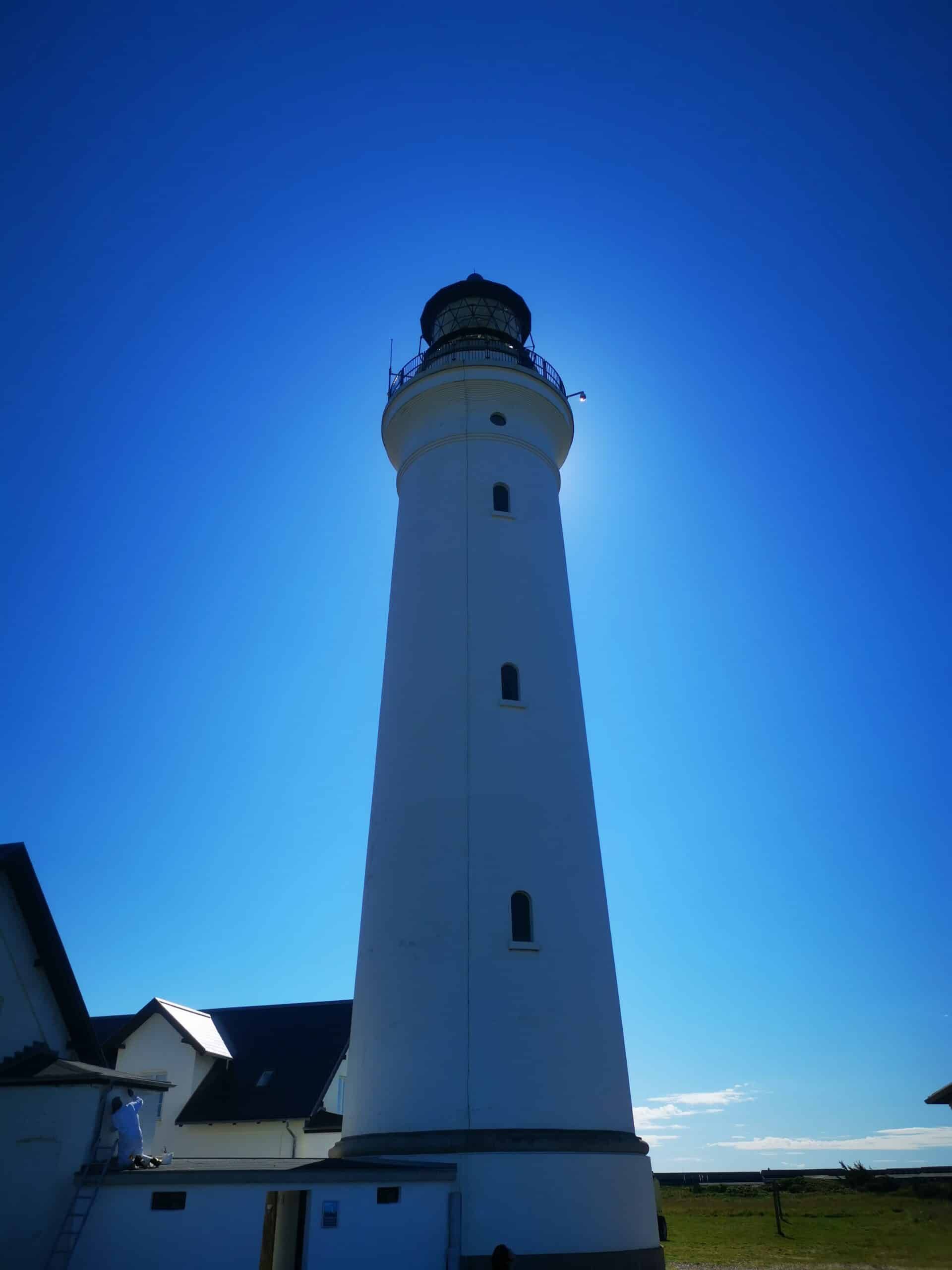 Ein weißer Leuchtturm mit blauem Himmel im Hintergrund.