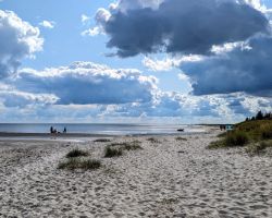 Ein Strand mit Sand unter einem bewölkten Himmel.